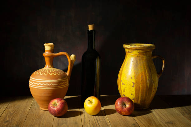 Still life, ceramic dish of apples and glass bottle on a wooden table