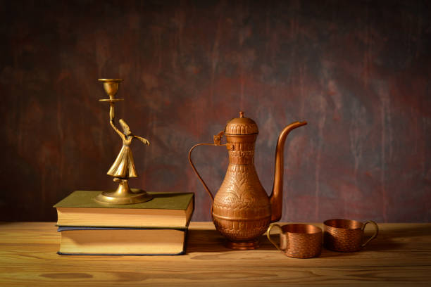 istock Still life, copper jug, copper cups, brass figure and books 2189323036