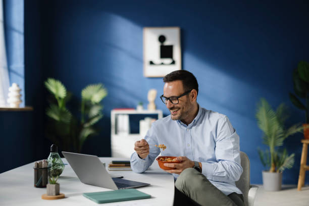 istock Happy male entrepreneur having a meal while working in the office. 2189327677
