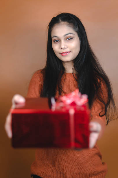 istock young woman holding red gift box. 2189330529