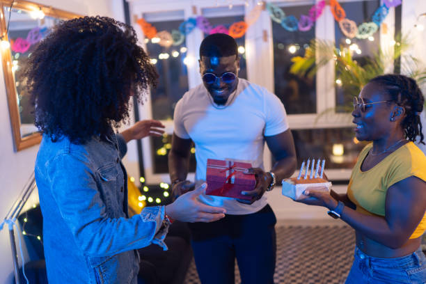 istock Friends surprising man with gift and cake at birthday party 2189333634