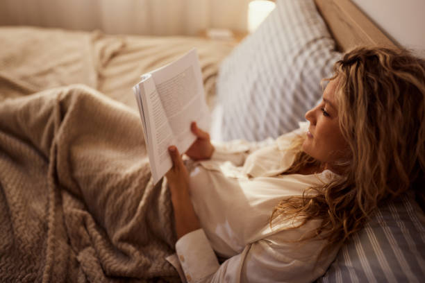 istock Relaxed woman reading a book in a bed. 2189334052