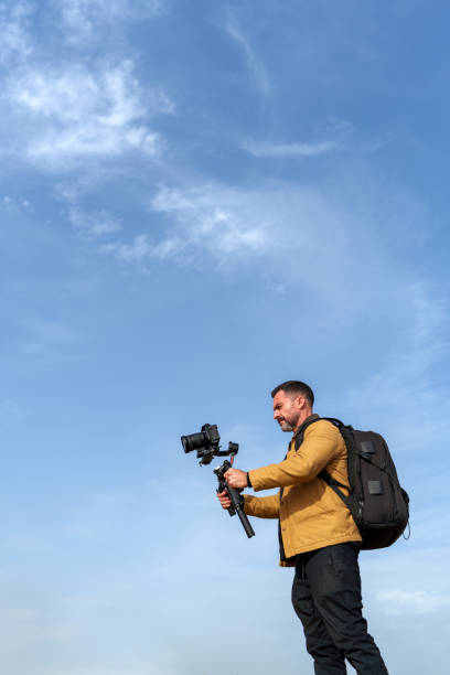 istock Videographer is recording using a gimbal and camera under a blue sky, capturing footage for a project 2189335148