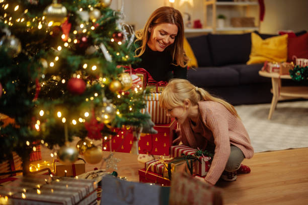 istock Little girl smiling while putting gifts under Christmas tree 2189338032