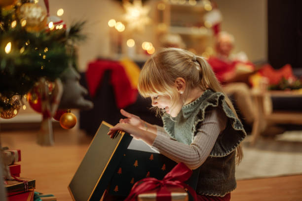 istock Cute little girl opening a mysterious Christmas present 2189338166