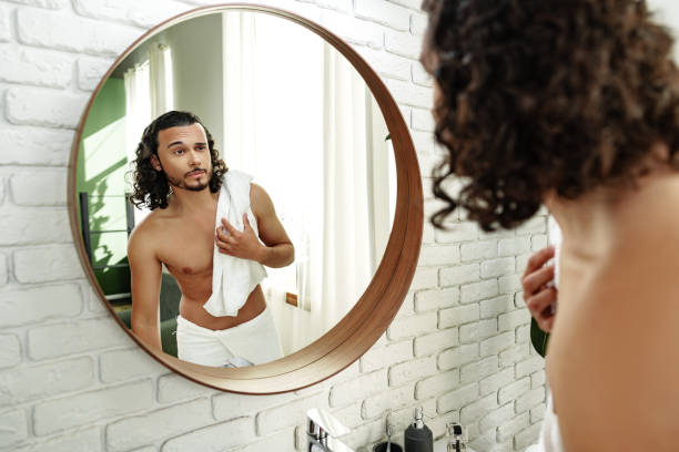istock Young man grooming himself in a modern bathroom mirror with natural lighting 2189341334