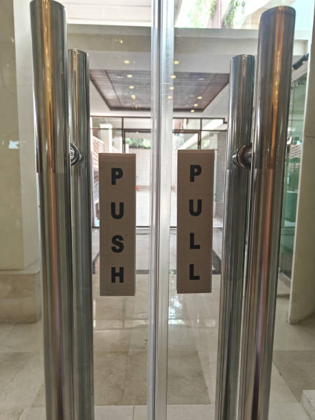 Signage on glass doors provides clear instructions for entering a modern building in a busy urban area