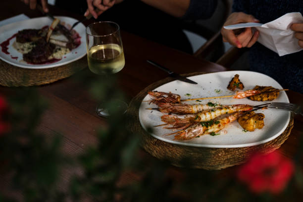 istock group having lunch or dinner, celebration eating, grilled shrimps, lamb chops, wine served table 2189345844