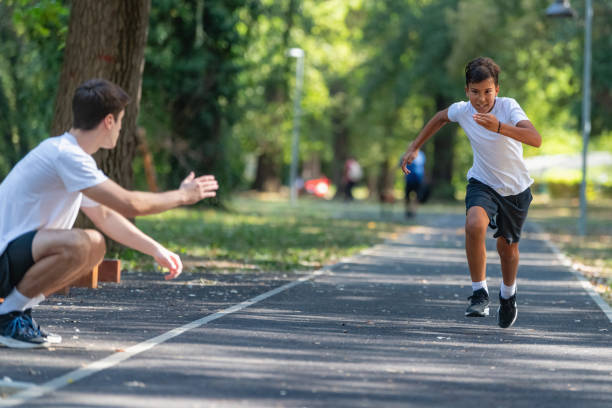 istock Trainer works with a boy to improve speed and running technique in the park. Focused on building agility and endurance, the outdoor training session promotes healthy physical activity for kids. 2189348009