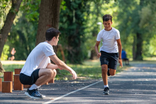 istock Trainer works with a young boy in the park, practicing speed running exercises. The boy focuses on improving his running technique and agility, under the coach's guidance. 2189348134