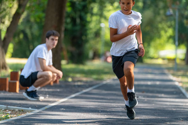 istock Trainer works with a boy to improve speed and running technique in the park. Focused on building agility and endurance, the outdoor training session promotes healthy physical activity for kids. 2189348210