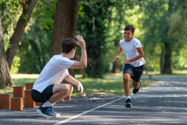 istock Trainer works with a young boy in the park, practicing speed running exercises. The boy focuses on improving his running technique and agility, under the coach's guidance. 2189348214