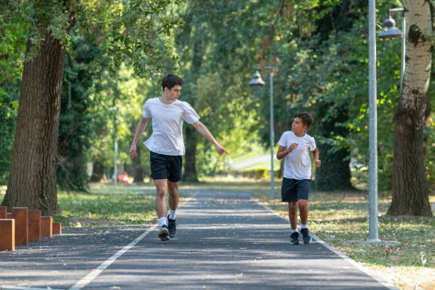 istock A personal trainer runs alongside a boy in a park, focusing on building endurance and promoting healthy exercise habits for children. The session emphasizes outdoor fitness and fun 2189348605
