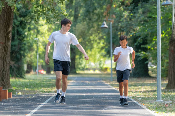 istock A personal trainer runs alongside a boy in a park, focusing on building endurance and promoting healthy exercise habits for children. The session emphasizes outdoor fitness and fun 2189348613
