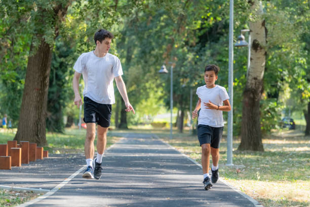 istock A personal trainer runs alongside a boy in a park, focusing on building endurance and promoting healthy exercise habits for children. The session emphasizes outdoor fitness and fun 2189348711
