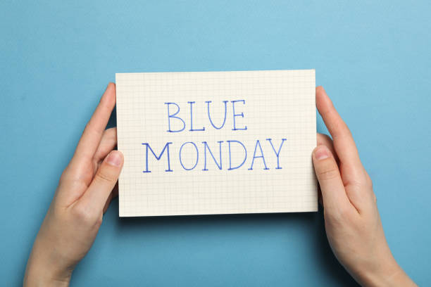 istock Paper with text Blue Monday in female hands on blue background, top view 2189354925