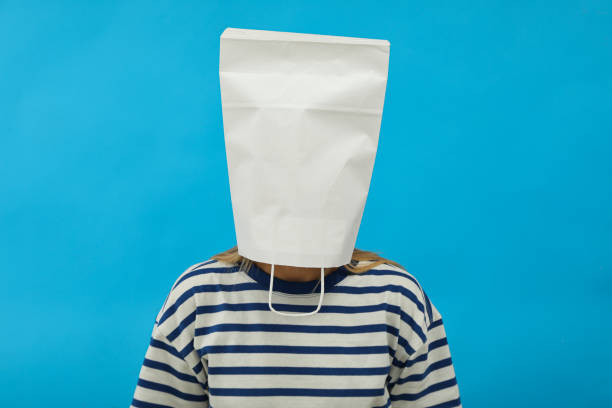 Girl with paper bag on head on blue background