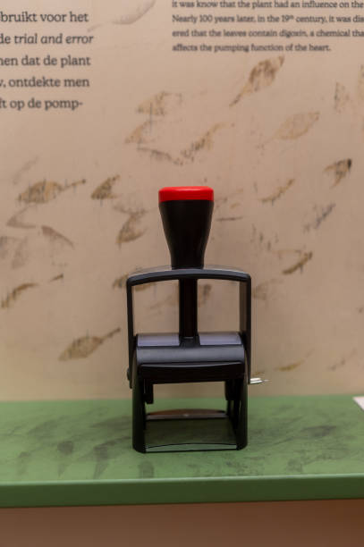 Black and red rubber stamp standing on a green surface in a museum, with informative text on the wall behind it