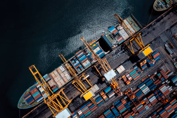 istock commercial port in deep sea load and unloading cargo from container ship import export by crane for distributing goods by trailers transport logistic  to customers and dealers, aerial top view 2189360796