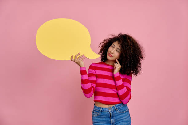 istock Young woman thinking and holding empty speech bubble on pink background 2189360899