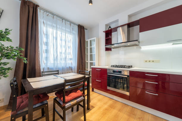 istock Scandinavian Style Cozy Modern Kitchen with Red and White Cabinets and Dining Area. Home Interior. Faucet, Fridge, Oven, Closet and Furniture in Background. 2189361886
