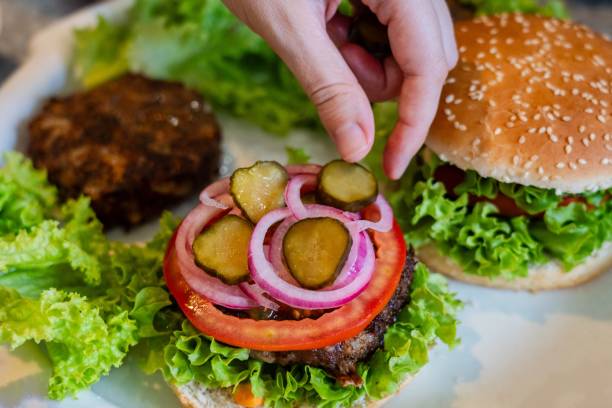 istock Close up view on preparing cheeseburger with vegetables and meat 2189362236