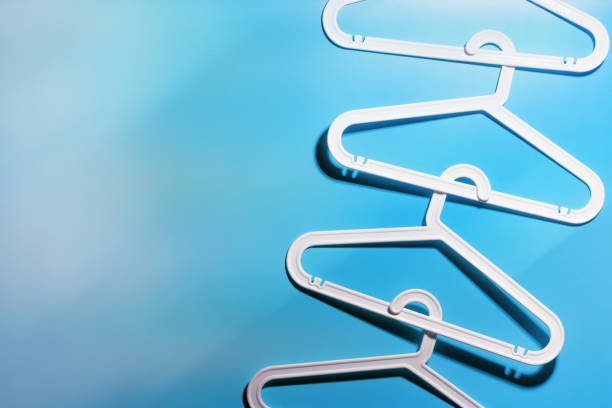 istock Top view minimal style pattern of white plastic hangers with hooks on blue background. Flatlay with Clothes racks for hanging garments. Minimal trend photo, lifestyle or interior design content 2189370614
