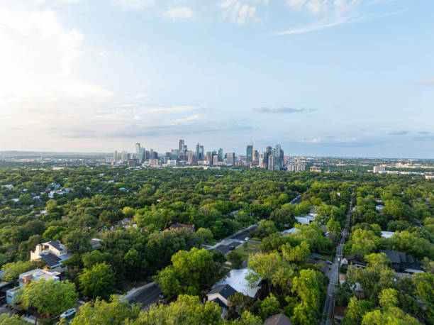 Aerial perspective of Austin, Texas skyline emerging above a verdant tree cover in a residential area, highlighting city's mix of urbanization and natural allure Aerial perspective of Austin, Texas skyline emerging above a verdant tree cover in a residential area, highlighting city's mix of urbanization and natural allure. west lake stock pictures, royalty-free photos & images