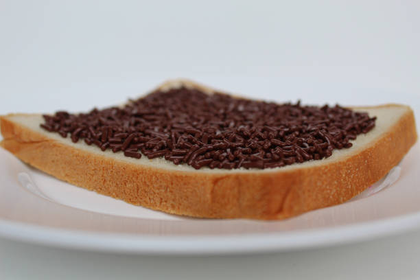 One slice of white square bread, with chocolate sprinkles spread, on white plate, isolated on white background