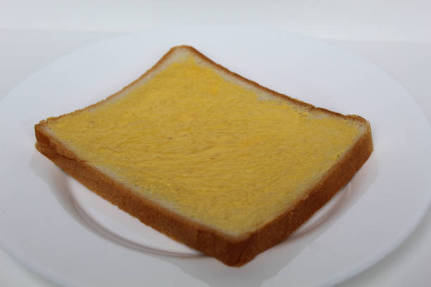 One slice of white square bread, with margarine spread, on white plate, isolated on white background
