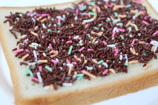 istock One slice of white square bread, with colorful chocolate sprinkles spread, on white plate, isolated on white background 2189374093