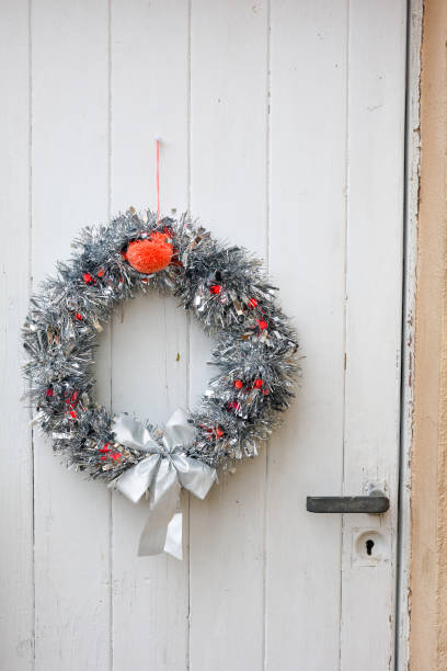 A big silver Christmas wreath is placed on a white door