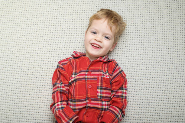 Thoughtful Little Boy in Red Plaid Shirt Relaxing on Cozy Surface