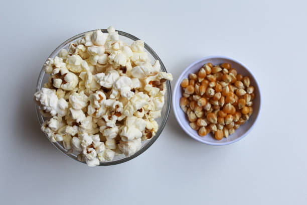istock Dried corn seed kernels and popcorn in bowl, before and after cooking, isolated on white background, flat lay or top view 2189377764