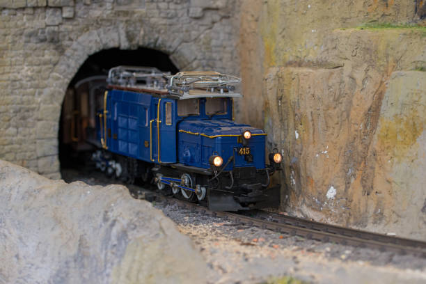 istock Blue model train exits stone tunnel during daytime model railroad operation 2189378492