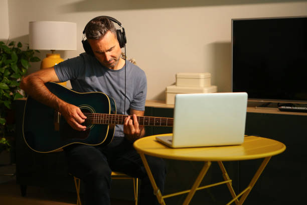 istock A man sitting in front of the computer practicing online music lessons 2189379080