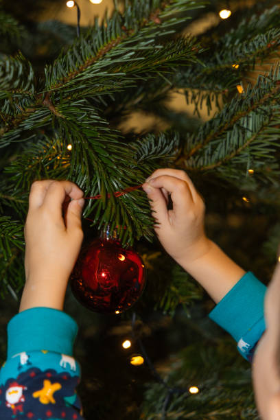 istock Hands of a child decorating the Christmas tree with a red ball 2189380768