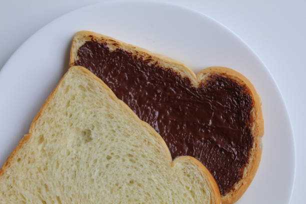 Two slices of white bread with chocolate spread or chocolate jam. Chocolate sandwich. On white plate, isolated on white background, flat lay or top view