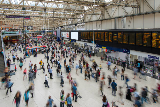 Crowds of travelers move through a bustling train station, checking departures on digital boards as they navigate the busy terminal during peak hours.