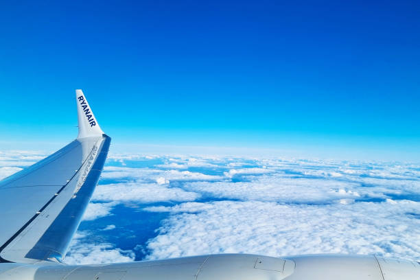 Girona, Spain, September 29, 2024: View from an airplane window showcasing broad wing and tail, featuring the airline's logo. below lies an expansive cloudscape beneath a vibrant, clear blue sky, suggesting themes of travel, adventure, and exploration.