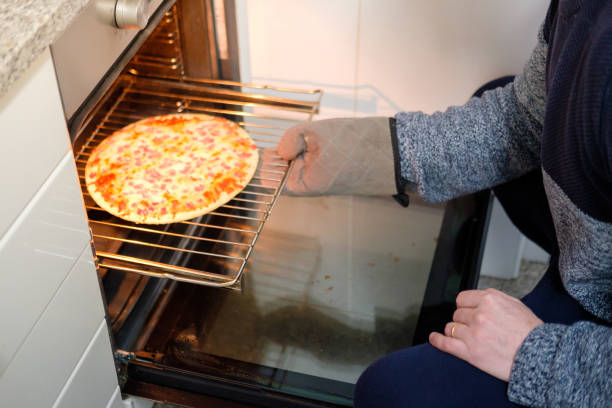 istock Man putting pizza in the oven at home 2189387513