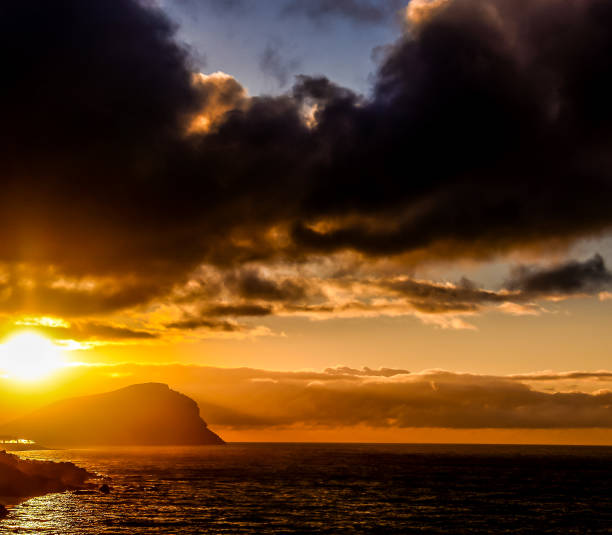 istock The sky is dark and cloudy with a bright orange sun in the background 2189391751