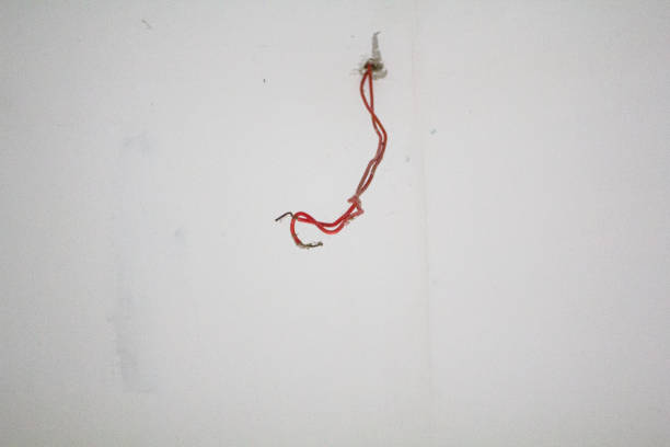 Close-up of exposed twisted network cables protruding from wall socket. Unfinished wiring work showing data cable installation or repair