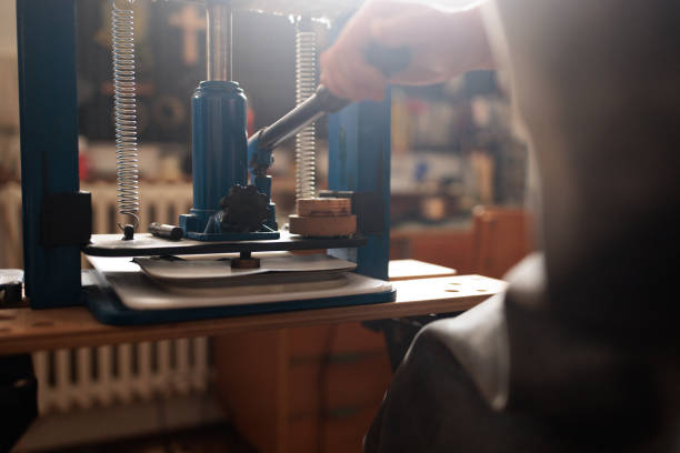 Craftswoman is focused on engraving a unique seal design onto a leather wallet.
