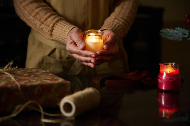 istock Hands holding a candle with holiday decor and a wrapped gift nearby 2189403719