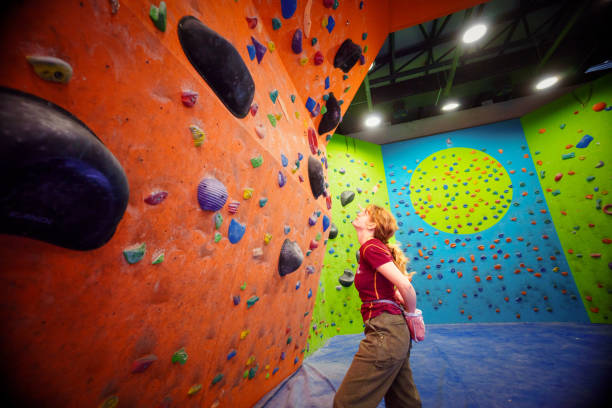 Young woman with long hair prepares for a climb on the vertical walls in a sport climbing gym