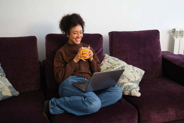 istock Young woman relaxing on the sofa, using laptop and drinking coffee 2189420919