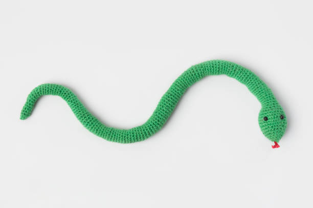 Knitted toy green snake on gray background.. Symbol of the year 2025.