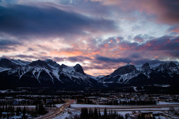 A view of the Town of Canmore in Alberta, Canada, in the wintertime. On the left is Ha Ling Peak, and on the right is Mount Rundle. The Trans-Canada Highway is visible at the bottom.