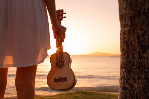 istock Woman holding ukulele at sunset beach. 2189430260